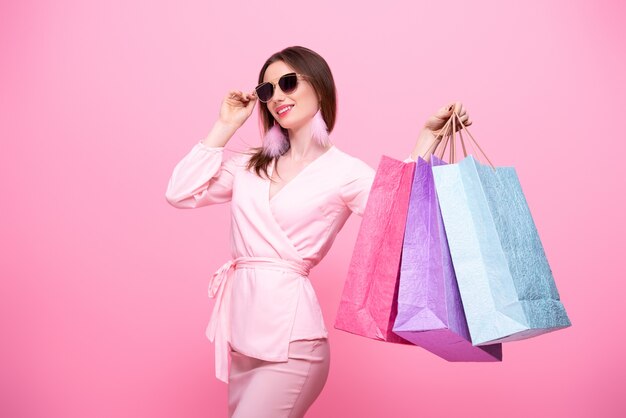 Fille élégante à la mode dans des lunettes de soleil avec des sacs à provisions multicolores