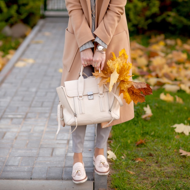 Fille élégante se promène dans le parc en automne dans un manteau beige et un chapeau