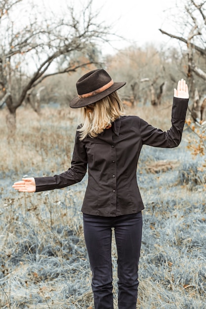 Fille élégante en vêtements noirs et un vieux chapeau dans le parc en automne.