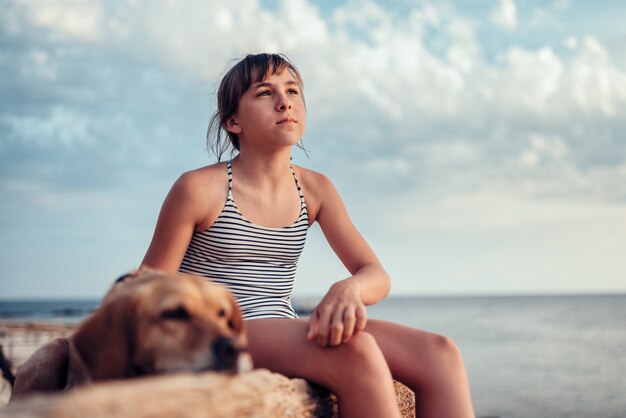 Fille embrassant son chien assis sur le rocher au bord de la mer