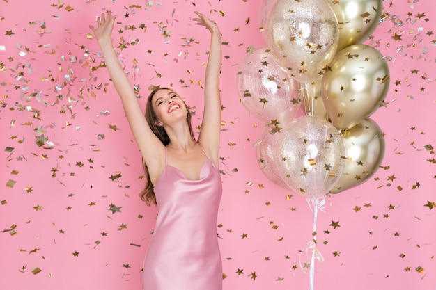 Une fille émotive célèbre le nouvel an ou un joyeux anniversaire avec des ballons à air lançant des confettis