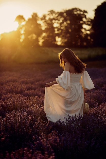 La fille enceinte avec un chapeau dans le champ de lavande au coucher du soleil