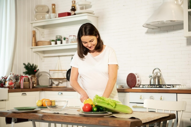 Une fille enceinte cuisine dans la cuisine à la maison