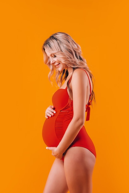 Fille enceinte dans le corps rouge et baskets blanches