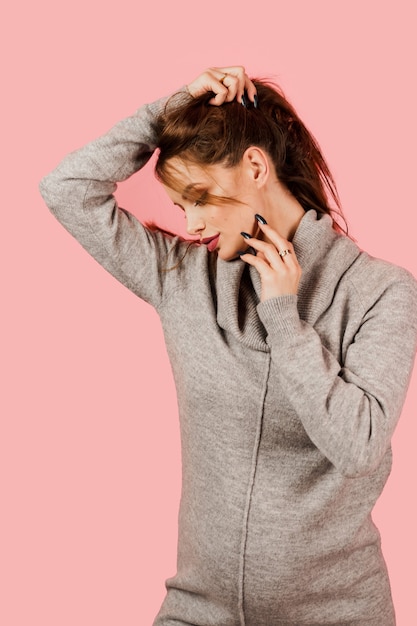 Fille enceinte dans un pull gris sur fond rose