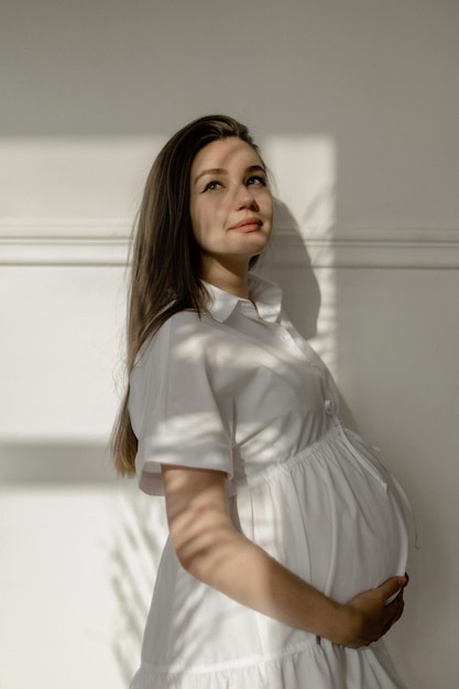 Fille enceinte dans une robe blanche avec des pivoines