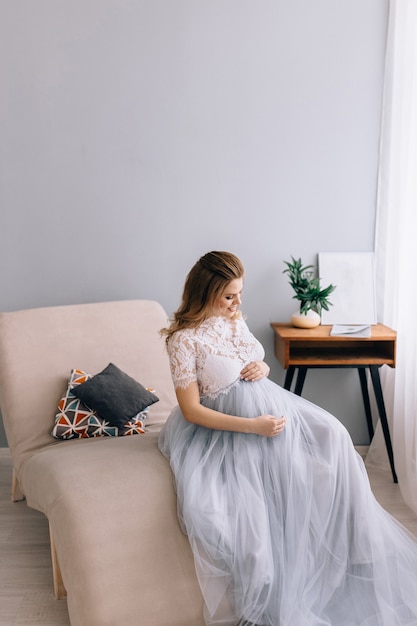 Fille enceinte est assise sur une chaise décorée