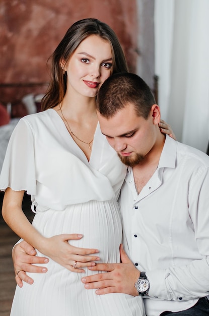 une fille enceinte est assise sur les genoux d'un homme