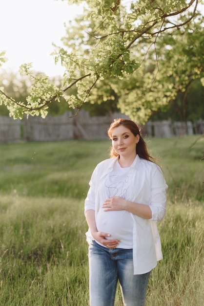 Fille enceinte en été à l'extérieur au soleil couchant