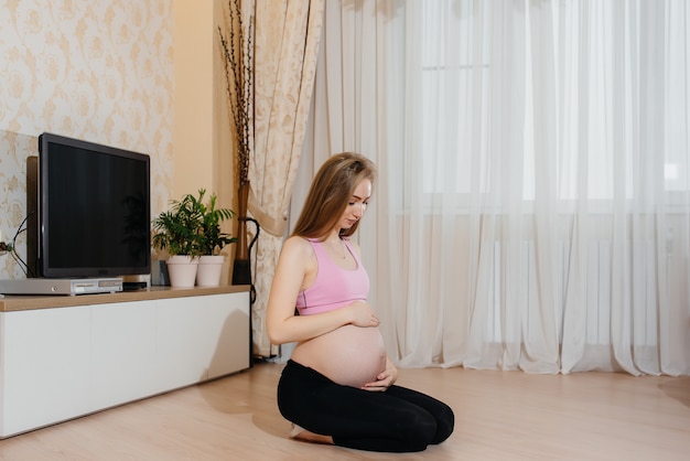 Une fille enceinte fait du yoga à la maison. Santé