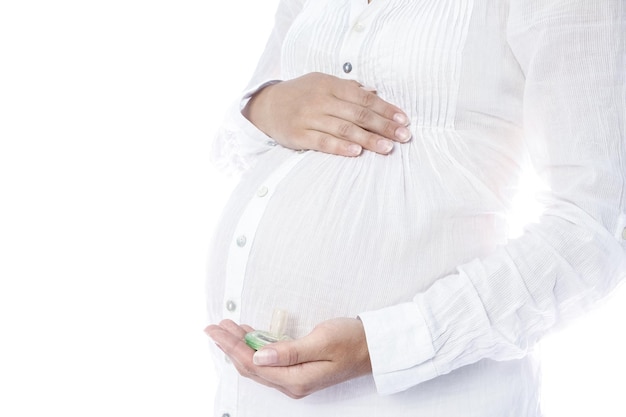 Une fille enceinte heureuse est allongée sur un fond blanc.