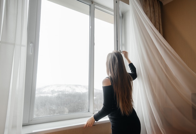 Une fille enceinte ouvre une fenêtre pour prendre l'air.