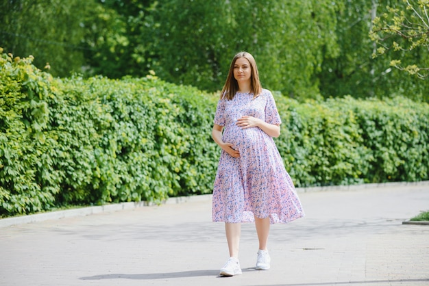 La fille enceinte à pied dans le parc de la ville