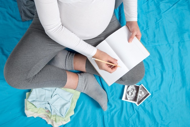 Photo une fille enceinte recueille les affaires des enfants les préparatifs d'un voyage à la maternité en attente de la naissance de l'enfant