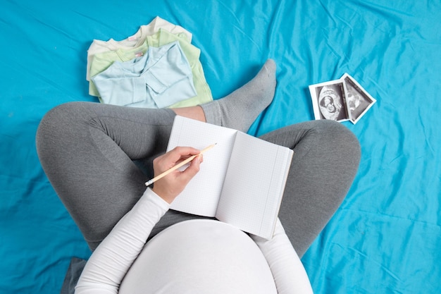 Une fille enceinte recueille les affaires des enfants Les préparatifs d'un voyage à la maternité En attente de la naissance de l'enfant