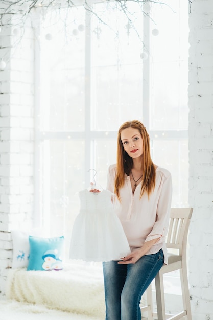 Une fille enceinte rousse dans un chemisier léger et un jean bleu