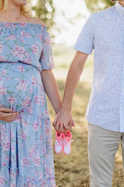 Fille enceinte avec son mari main dans la main dans la nature sur le terrain