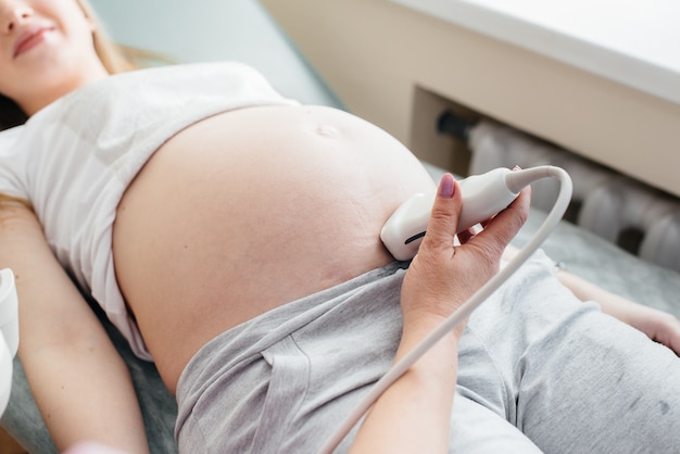 Une Fille Enceinte Subit Une échographie De L'abdomen à La Clinique En Gros Plan. Examen Médical