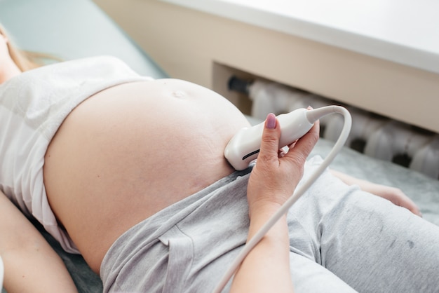 Une fille enceinte subit une échographie de l'abdomen à la clinique en gros plan. Examen médical