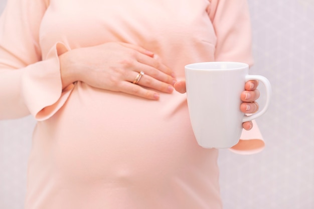 Une fille enceinte tient un verre d'eau à la main. attente d'un enfant, maternité.