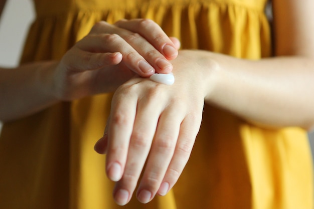 La fille enduit ses mains de soins de la peau crème cosmétique