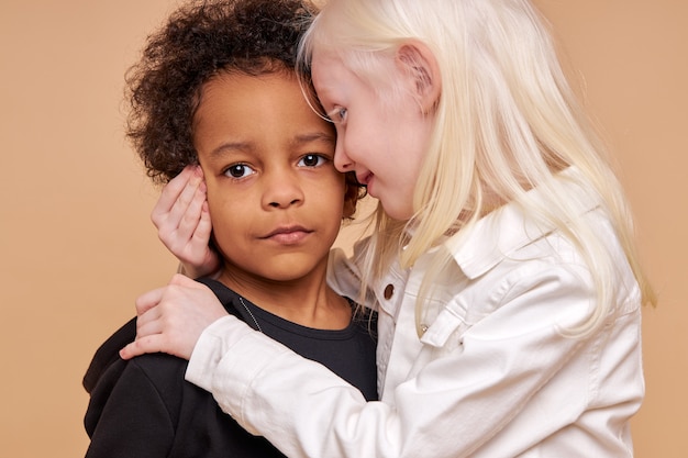 Fille enfant albinos sensible embrasse garçon africain isolé