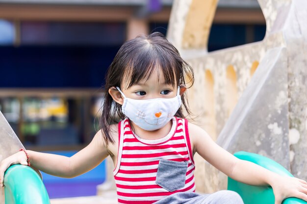 Fille enfant asiatique heureuse souriant et portant un masque en tissu.