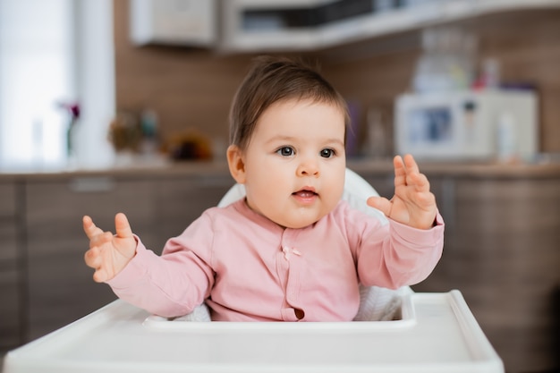 Fille enfant en bas âge est assis dans une chaise d'enfant dans la cuisine