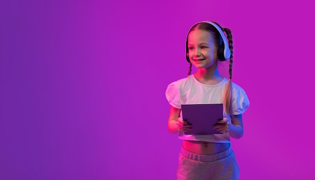 Fille enfant blogueuse utilisant une tablette numérique et un casque sans fil