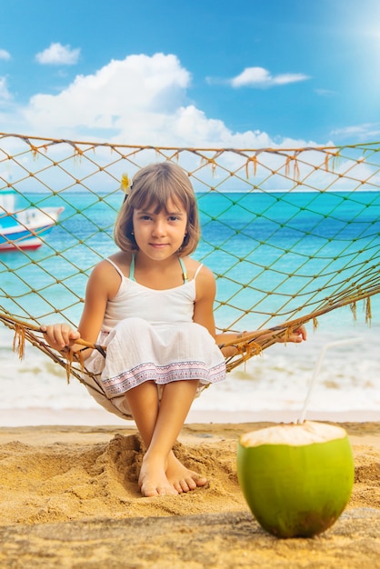 Fille enfant boit de la noix de coco sur la plage