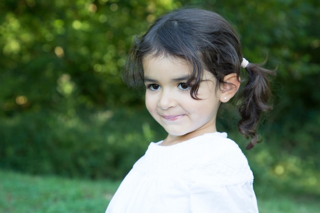 Fille enfant brune amusante dans la nature fond vert sur parc ou jardin