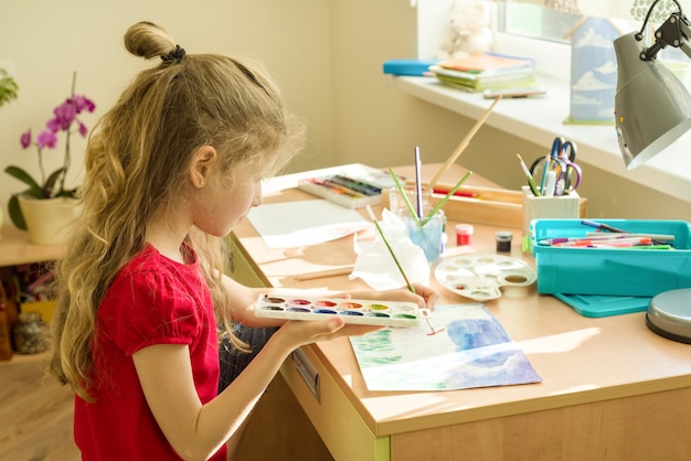 Fille enfant dessin aquarelle à la table à la maison