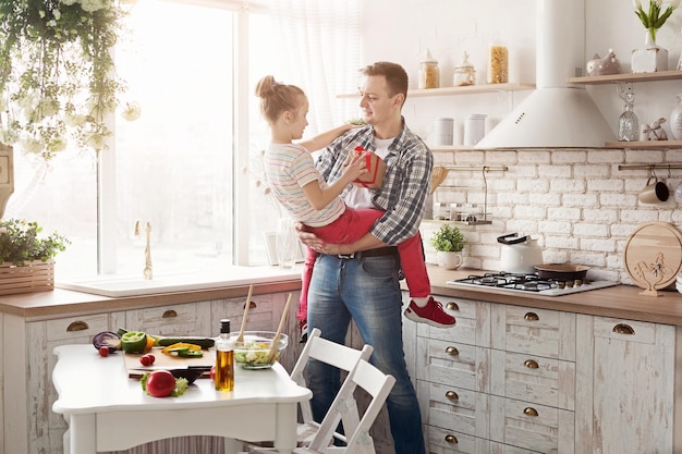 Fille enfant donnant un cadeau à son père dans la cuisine de la maison. Bonne famille aimante et concept de fête des pères.