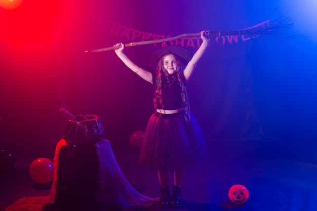 Fille enfant drôle en costume de sorcière pour halloween avec citrouille jack et balai