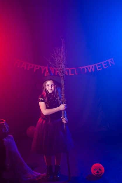 Fille enfant drôle en costume de sorcière pour Halloween avec citrouille Jack.