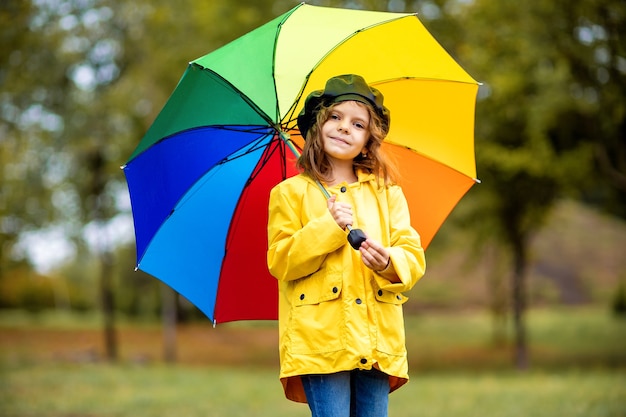 Fille enfant drôle heureux avec parapluie multicolore dans des bottes en caoutchouc au parc automne.