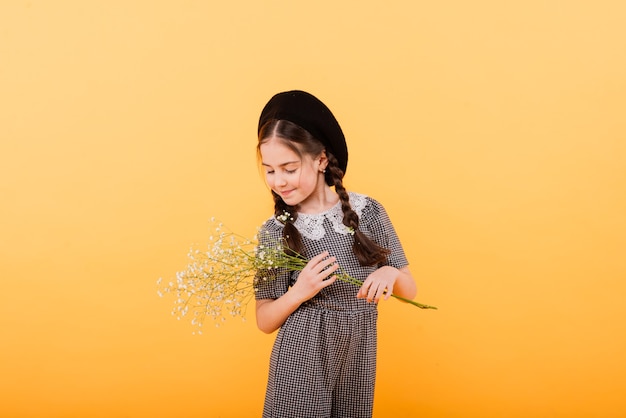 Fille enfant drôle souriant avec bouquet de fleurs sur un fond coloré