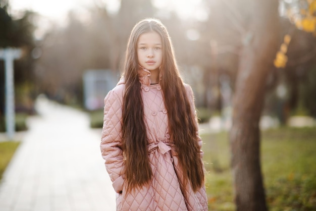 Fille enfant élégante de 1012 ans porter une veste avec de longs cheveux blonds debout dans le parc Saison d'automne Enfance