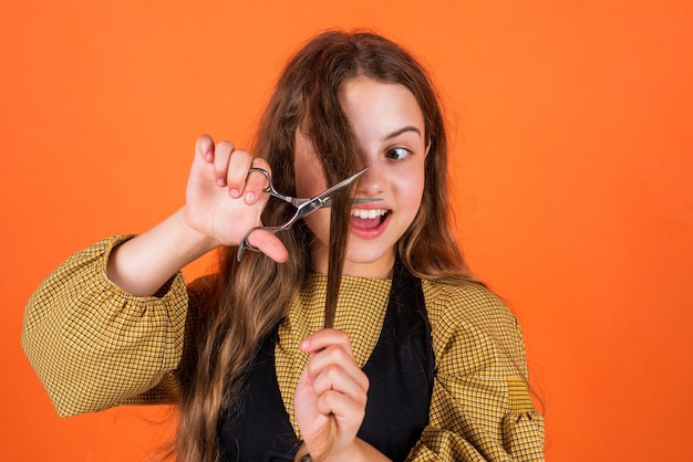 Fille enfant élégante va couper les cheveux avec un coiffeur de ciseaux