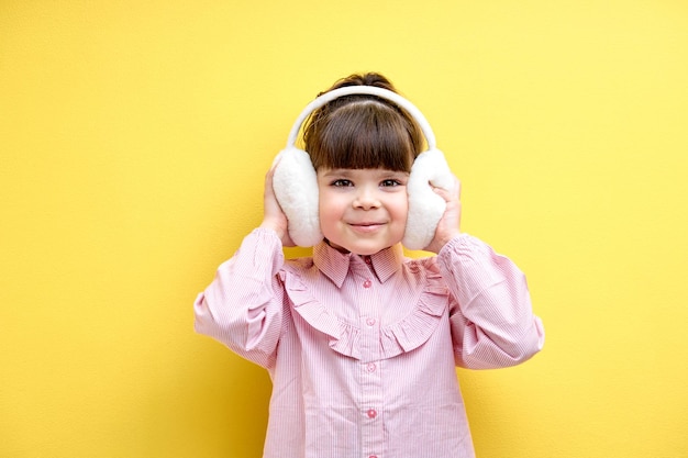 Fille enfant émotionnelle positive aime écouter de la musique portant un casque isolé sur fond jaune...