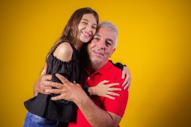 Fille enfant étreignant son grand-père. Père et fille sur fond jaune. Fête des pères. fête des grands-pères