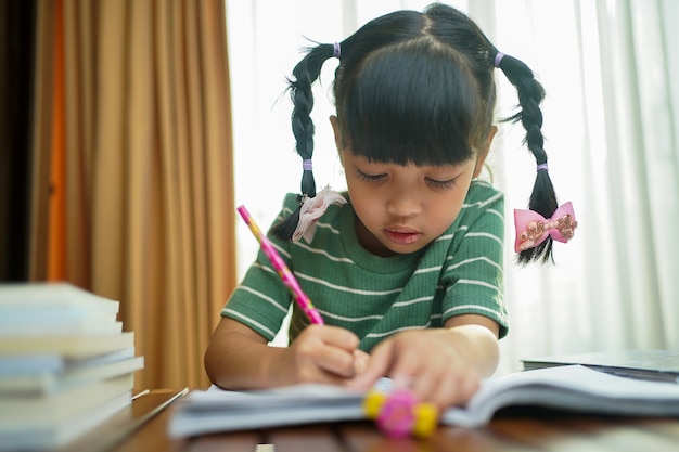 Photo fille enfant étudiante asiatique écrit sur le livre papier.