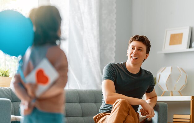 La fille de l'enfant félicite son père et lui donne une carte postale Papa et fille sourient