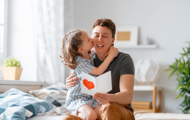 La fille de l'enfant félicite son père et lui donne une carte postale