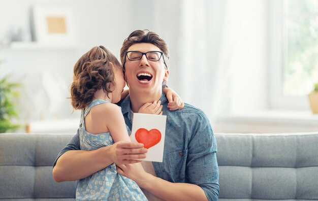 La fille de l'enfant félicite son père et lui donne une carte postale