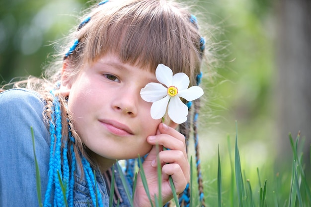Fille enfant heureuse appréciant la douce odeur de fleurs de narcisse blanc dans le jardin d'été