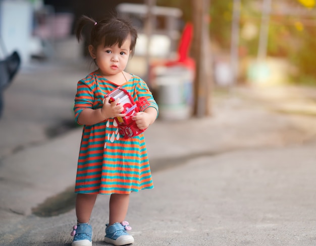 Fille enfant heureux avec un jouet de voiture, enfant mignon jouant à l'extérieur.