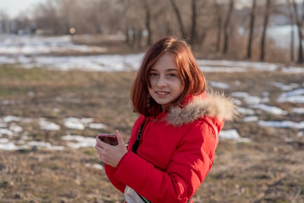 Fille enfant hiver à la recherche de téléphone mobile. Fille de 9 ans en hiver regarde le téléphone.