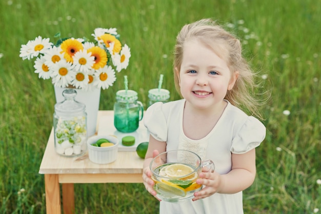 Fille enfant avec limonade. Limonade et fleurs de marguerite sur table.