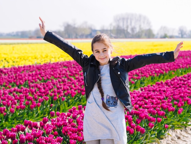 Fille enfant mignon aux cheveux longs sur les champs de tulipes